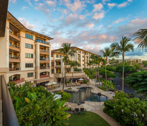 The image shows a resort scene with buildings, greenery, and a pool under a colorful sky. A relaxing tropical atmosphere is evident.