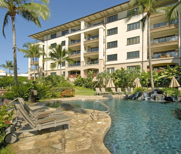 The image features a resort-style pool surrounded by tropical plants and loungers, with a multistory building in the background.